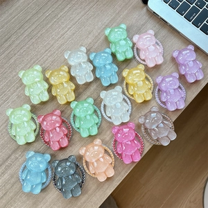 Colorful glitter bear-shaped magnetic phone grip sockets on a wooden desk with a laptop