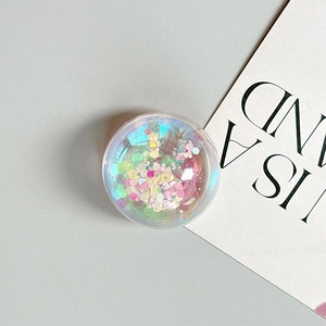 Close-up of a round transparent phone grip with colorful holographic sequins inside