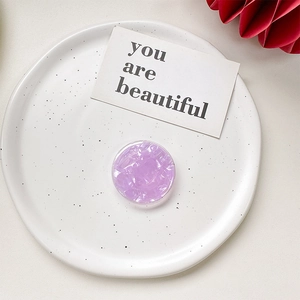 Detailed top view of a purple shell-texture collapsible grip on a white ceramic plate