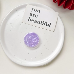 Detailed top view of a round purple marble textured pop socket on a ceramic plate