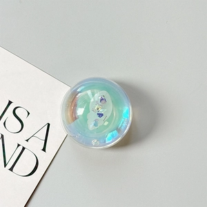 Macro shot of holographic shell-shaped phone grip with glitter on grey background