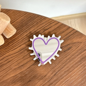 Detailed view of heart-shaped Y2K mirror phone grip with purple outline on wood surface