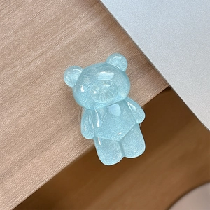 Close-up of a blue glittery resin bear phone grip on a minimalist wooden desktop