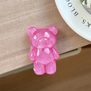 Detailed macro view of a glittery pink bear-shaped phone grip on a white ceramic tray