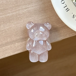 Close-up of translucent purple resin bear phone grip with glitter finish on wood background