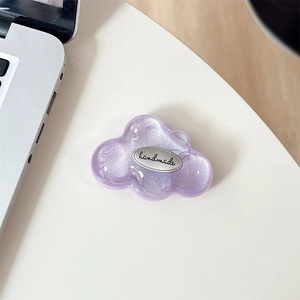 Detail view of a purple glitter cloud phone grip with a handmade silver emblem