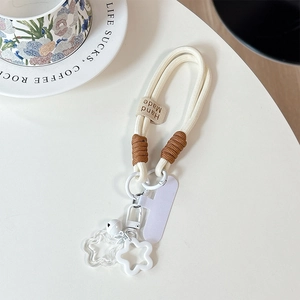 Detail of handmade cream woven phone strap with star charms and leather 'Hand Made' tag