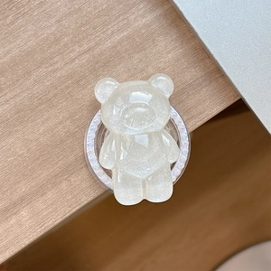 Detailed view of a white glitter bear phone grip with iridescent finish and pearl trim