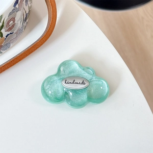 Close-up of mint green glitter cloud phone grip with handmade silver plaque