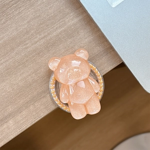 Detail of a cute translucent pink glitter bear phone grip with pearl ring ornament