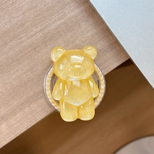 Detail of yellow glitter bear phone socket holder with pearl base on wooden desk