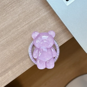 Detail of a purple glitter bear phone socket with pearl base on a wooden desk