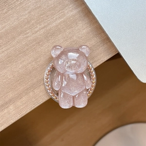 Close-up of pink glitter bear phone grip with decorative gold pearl trim on base