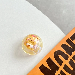 Macro shot of a yellow resin ball phone grip featuring a cute bear with pink flowers