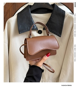 Detail shot of brown leather mini bag with wavy flap design and thin shoulder strap