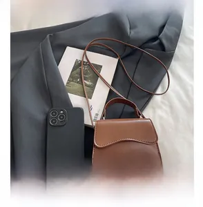 Mini brown leather crossbody bag shown next to a smartphone to demonstrate its compact size