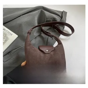 Detailed view of brown suede half-moon shoulder bag with adjustable leather strap