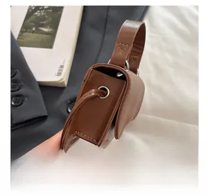 Detail view of the brown leather mini bag's side metal eyelets and premium texture