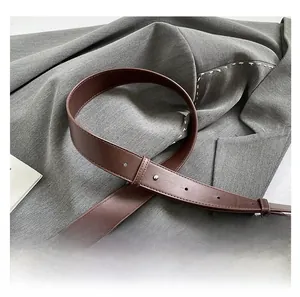 Detail of adjustable dark brown leather shoulder strap with polished metal buckle and stitching