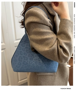 Detail der blauen Hobo-Tasche mit Leopardenmuster, getragen zu einem modischen Wollmantel