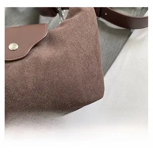 Detailed close-up of brown suede and smooth leather textures with metal buckle on handbag