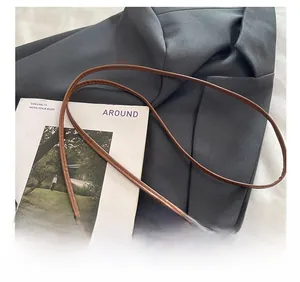 Detail showing the brown leather shoulder strap with neat stitching on a grey blazer