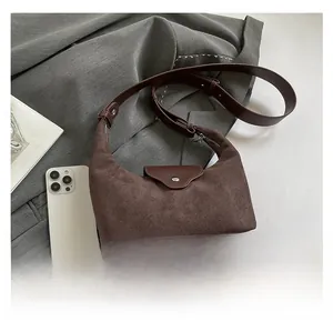 Detailed texture of brown suede hobo bag with leather strap on grey blazer background