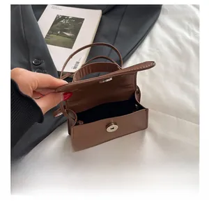 Detail showing brown leather mini crossbody bag with magnetic clasp and black lining