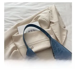 Detail der blauen Hobo-Tasche mit Leopardenmuster und Prägung auf beigem Blazer