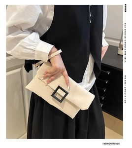 Detail of cream envelope clutch with a black square buckle and detachable wrist strap