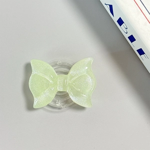 Macro view of mint green glitter bow phone grip with clear retractable base on desk