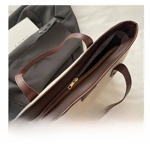 Close-up of smooth gold metal zipper closure on canvas and brown leather tote bag