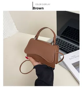 Detail of a brown matte PU leather crossbody bag with stylish wave-edge flap design