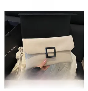 Close-up of cream envelope clutch bag featuring black square buckle and wrist strap