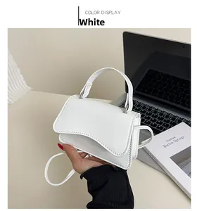 Detail of a white mini square crossbody bag with unique wavy curved flap design