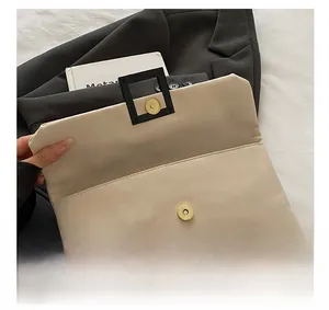 Detail view of premium gold magnetic clasp and interior flap on off-white envelope bag
