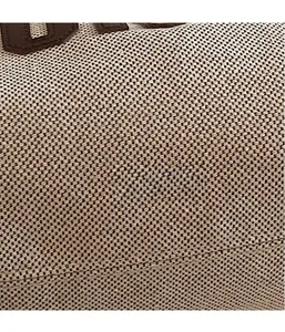 Close-up of the beige canvas fabric texture and brown leather trim with fine stitching