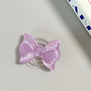 Detailed view of purple glitter bow-shaped MagSafe phone grip with collapsible base