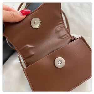 Close-up of brown faux leather crossbody bag showing magnetic snap closure and interior