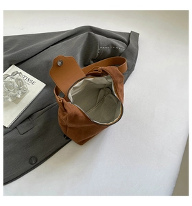Detail view of brown suede half-moon bag with internal zip pocket and magnetic closure