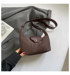 Detail of dark brown matte texture and metal buckle on minimalist shoulder bag