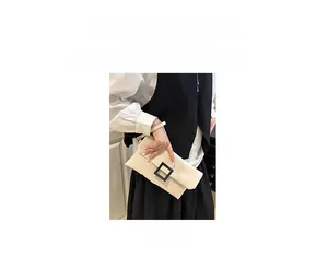 Detail of minimalist cream clutch bag with matte black square buckle and handheld strap