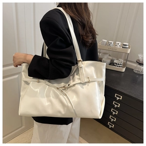 Detail of white glossy leather tote bag with slim shoulder strap shown in home setting