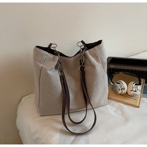 Detailed shot of large canvas tote bag with leather strap and metal chain on white cloth