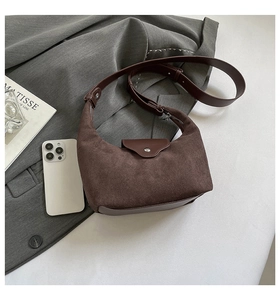 Detail of dark brown matte hobo bag with suede texture and leather strap on gray blazer