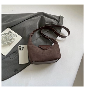 Detail of retro brown suede saddle bag with smooth leather trim and adjustable shoulder strap