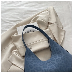Detail of blue leopard print shoulder bag with crescent shape and embossed logo