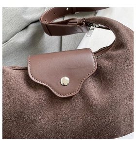 Close-up of vintage brown half-moon bag featuring suede texture and silver metal buckle
