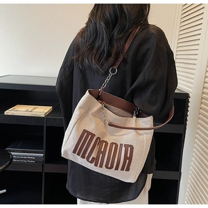 Detail of canvas tote bag with brown leather chain strap and large MCRDIR print