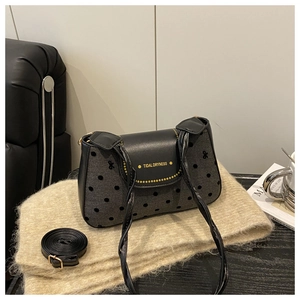 Détail du sac bandoulière gris à pois, finitions en cuir noir et logo doré